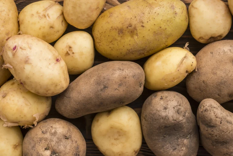 Close-up of yellow and brown potatoes resting on a dark wooden surface.